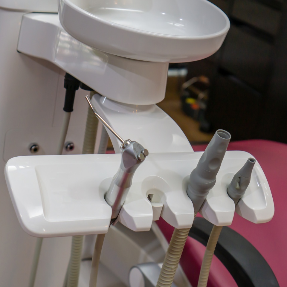 Closed up Dental tools for cleaning in machine holder against Professional dental chair at dentist clinic. Modern technology for dentistry.